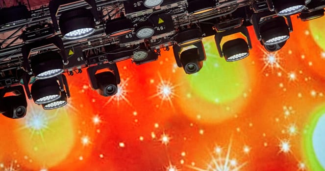 A lot of spotlights on the ceiling of the concert hall. Bright stage lights are on. The spotlights are arranged in a grid pattern. The stage is dark. The spotlights are creating a dramatic effect.