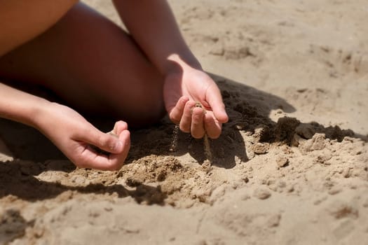 Close up of kid hands digging on the beach sand. Summer concept