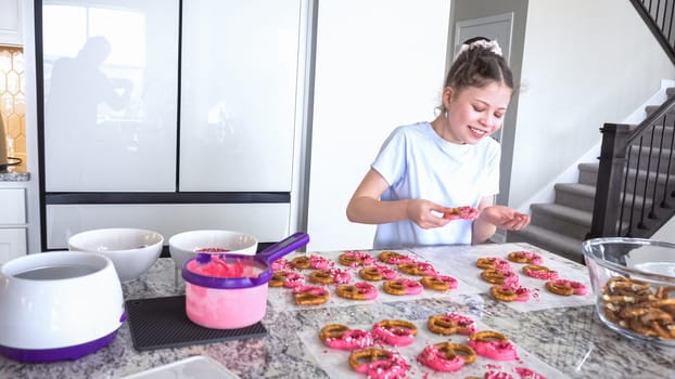 With focused attention, this budding culinary artist dips pretzels into a pot of melted chocolate, creating sweet delights in the warmth of a well-lit home kitchen.