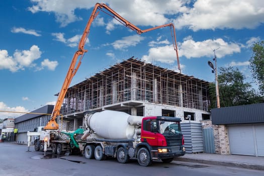 A concrete pump truck takes concrete from a concrete mixer truck and pours the floor at a construction site.