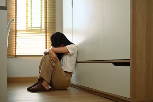 Upset teenage girl sitting on floor feeling lonely and sad. Psychological and mental health concept.