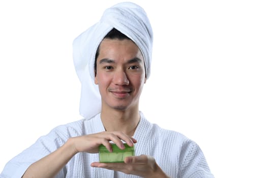 Portrait of handsome man in bathrobe holding a jar of aloe vera gel on white background. Men cosmetics and skincare concept.