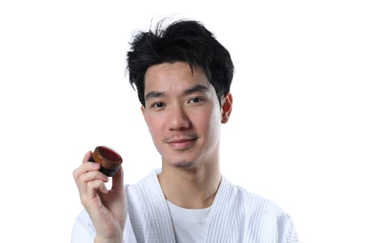 Handsome man holding jar with pomade or wax for hair styling on white background. Hair care and cosmetics for men.