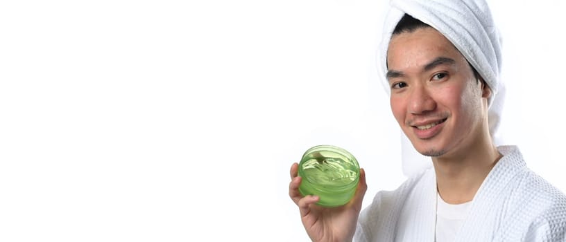 Young Asian man holding a jar of aloe vera gel isolated on white background. Cosmetics products for men concept.