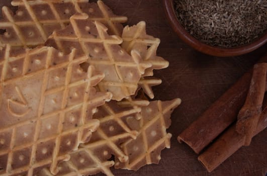 Delicious crunchy cinnamon biscuit. Dark background.Still life. Wooden bowl with anise seeds and cinnamon sticks