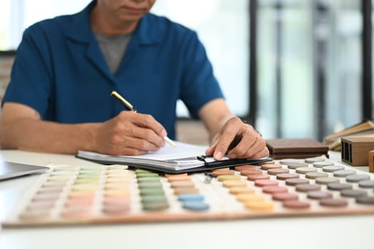 Unrecognizable senior male Interior designer choosing best paint for home refurbishment.