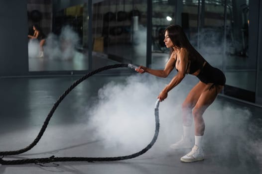 Caucasian woman doing exercise with ropes. Circuit training in the gym