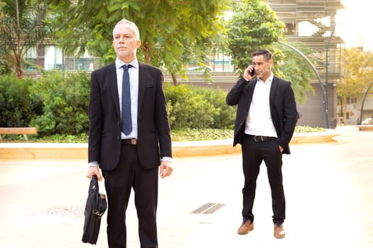 Two trusted business colleagues dressed in formal attire with a mobile phone finishing up the meeting for a business project