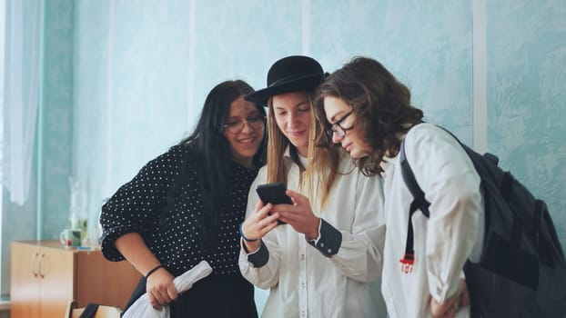 Three high school students discussing something on a smartphone