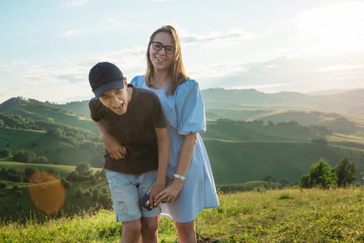 Portrait of happy mother and son tourists in a beauty mountain valley at sunset