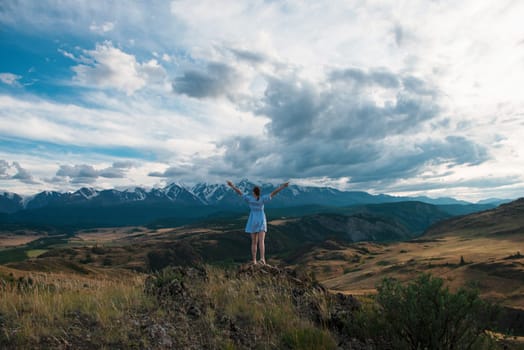 Woman in blue dress in summer Altai mountains in Kurai steppe