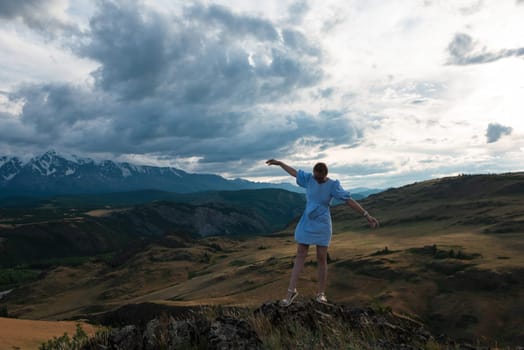 Woman in blue dress in summer Altai mountains in Kurai steppe