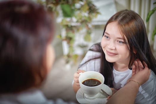 Happy Overweight family with mother and daughter drinking tea or coffee in room. Middle aged woman and teenager girl having fun and joy