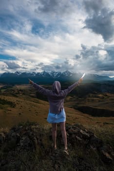 Woman with flashlight in summer Altai mountains in Kurai steppe