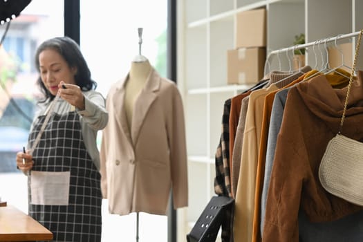 Middle age asian woman small business owner working in her clothing store.