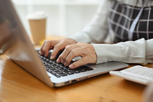 Cropped shot small business owner checking online orders on laptop computer.