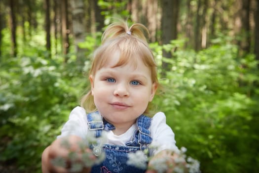 Pretty girl holds out a bouquet of flowers. Love for parents, for nature. Taking care of toddler children