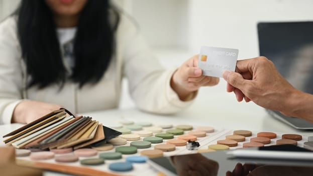 Cropped shot of female costumer making payment with credit card with contractor for services.