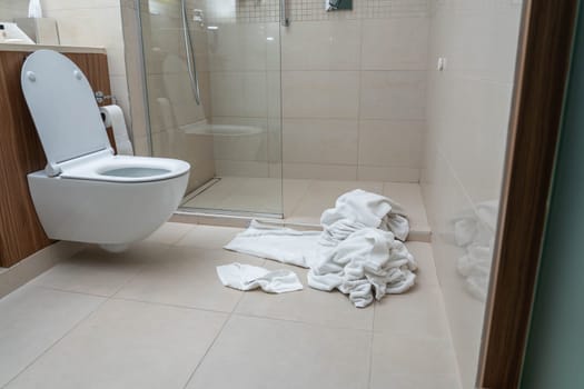 Dirty used towels on the floor in hotel bathroom. Housekeeping replace only the used towels on