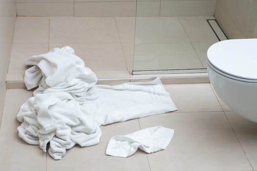 Pile of dirty used towels on the hotel bathroom floor. Housekeeping replace only the used towels on