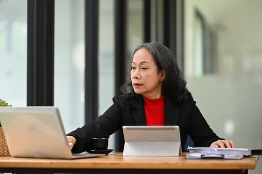 Mature entrepreneur sitting at desk and working with laptop computer.