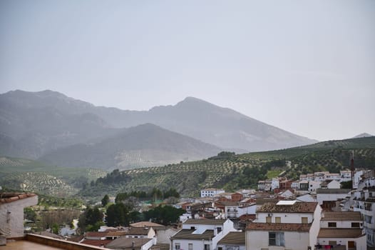 View of beautiful medieval district of Spanish village, Quesada in the region of Jaen, Andalusia, Spain in mountains. White houses with red tiles over mountain ridge background of La Sierra de Cazorla