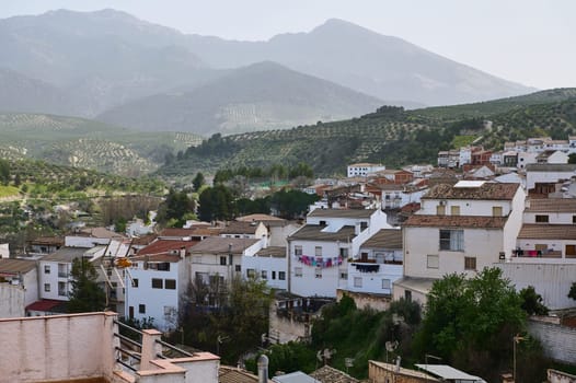 View of beautiful medieval district of Spanish village, Quesada in the region of Jaen, Andalusia, Spain in mountains. White houses with red tiles over mountain ridge background of La Sierra de Cazorla