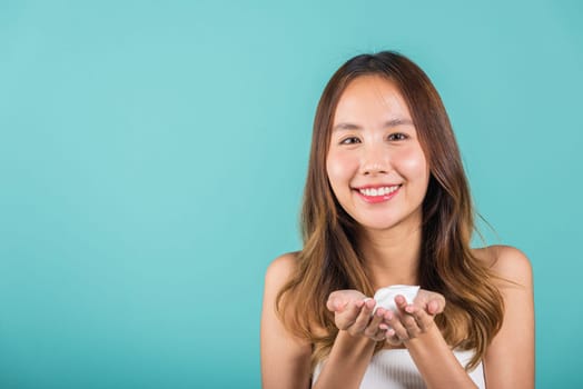 Portrait Asian young woman hands are adorned with white foam mousse studio shot isolated on blue background, beautiful female holding cleansing foam daily self care routine, beauty skincare concept