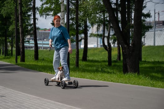 Caucasian woman rides an electric longboard with her Jack Russell Terrier dog