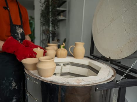 Close-up of a man's hands loading ceramics into a special kiln