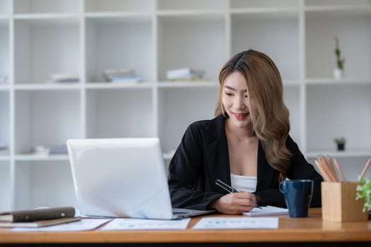 Beautiful accountant sitting working with laptop calculating financial and tax figures for company on desk in living room..