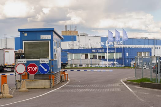 Vilnius, Lithuania - June 5, 2023: A view of the gate entrance to a large logistics and transit center in Lithuania. The blue building is marked with the words Logistikos ir Tranzito Centras and Muitine.