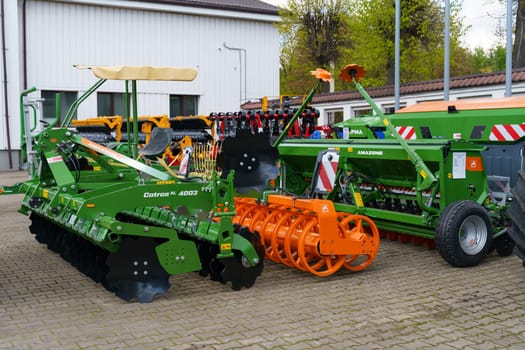 Vilnius, Lithuania - June 5, 2023: A close-up shot of agricultural machinery parked on a paved surface. The machinery is primarily green with black and orange accents.