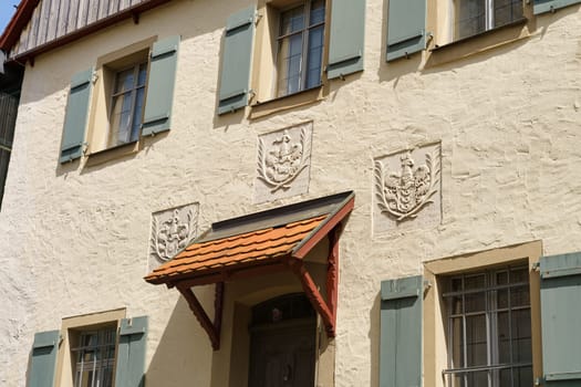 Feuchtwangen, Germany - June 6, 2023: A white building with green shutters and ornate reliefs on the facade.