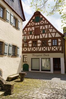 Feuchtwangen, Germany - June 6, 2023: A traditional butcher shop with a sign that reads Metzgerei Beck is located in a charming cobblestone alleyway in Germany. The buildings timber framing and decorative details are a beautiful example of the regions architectural style.