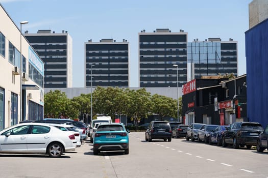 Barcelona, Spain - June 8, 2023: Cars parked in a row on a street in front of large, modern office buildings in a Spanish city.