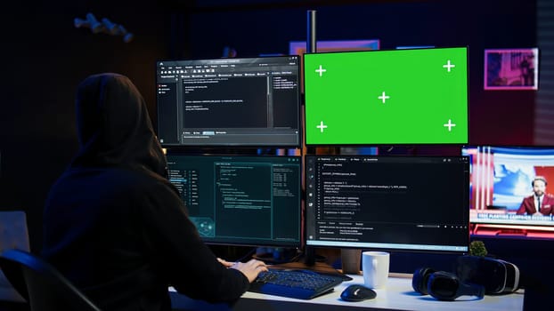 Dangerous man hacking using green screen PC, stealing credit card numbers and infiltrating banking systems. Hacker running code in apartment on mockup computer display, camera B