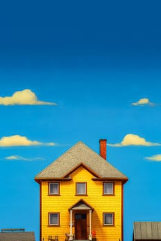 A yellow house with a blue roof and blue trim. The house is tall and has a chimney