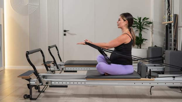 Pregnant woman doing Pilates exercises on a reformer machine