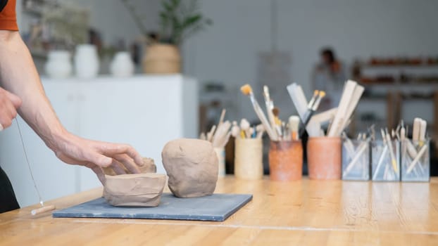 A potter cuts a piece of clay into pieces before using it in the workshop