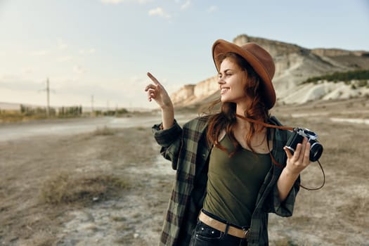 Stylish woman in hat capturing the viewer's gaze with a camera