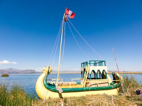 Vibrant reed boat with peruvian flag floating on the serene waters of lake titicaca under blue skies