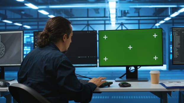 Engineer in server hub using green screen PC to repair equipment storing datasets. Professional using mockup computer to do debugging on rigs doing computational operations