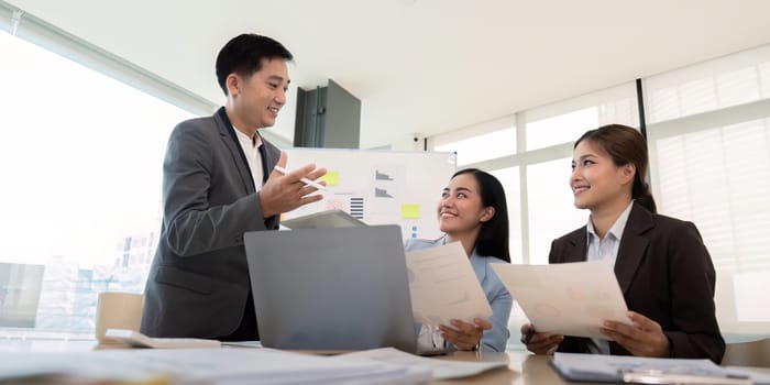 Business team discussing strategy with documents in hand in a modern office setting, emphasizing leadership, teamwork, and effective communication