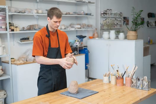 A potter kneads clay before using it in the workshop. Close-up of a man's hands