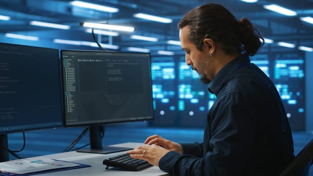 System administrator working in high tech server room capable of storing vast amounts of data, using computer. IT engineer typing on PC keyboard, upgrading servers controlling network resources