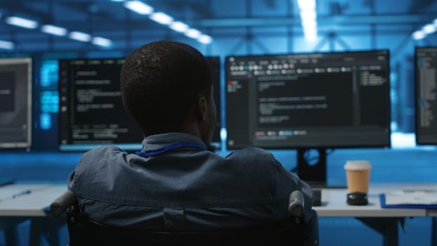 African american person with impairment in server farm ensuring data remains shielded from threats. Close up shot of wheelchair user safeguarding data center hardware against unauthorized access