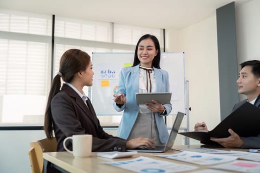 Business team engaging in a strategy meeting using a tablet in a modern office setting, emphasizing leadership, teamwork, and effective communication