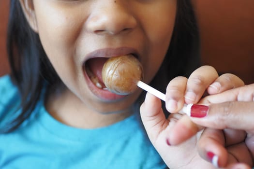 child is licking colorful candy on stick,