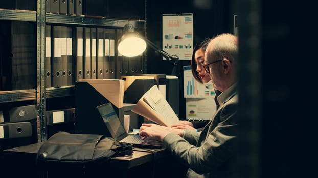 Team of private officers reading confidential folders with important federal information, using classified records to create a criminal profile. Agents working with bureaucracy documents. Camera A.